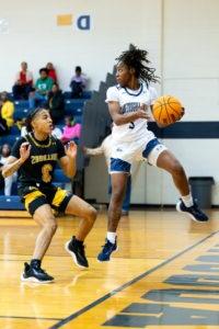 Female SAU Basketball player jumping while catching basketball and defending against opponent